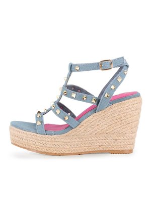 Sandalia cuña con tiras de mezclilla azul que presentan tachuelas doradas, plataforma de yute trenzado y una plantilla rosa. Diseño de punta abierta, correa ajustable en el tobillo.