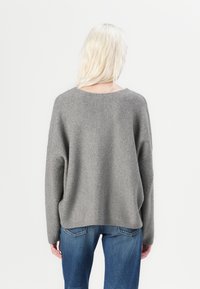 Γκρι, ριγωτό πο�υλόβερ με χαλαρή εφαρμογή και φαρδιά λαιμόκοψη, σε συνδυασμό με μπλε denim τζιν. Μαλακή υφή, casual σχέδιο και ριγμένα μανίκια.