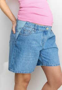 Shorts de mezclilla en azul claro, con un clásico diseño de cinco bolsillos y una cinturilla ancha con un panel contrastante en azul claro.