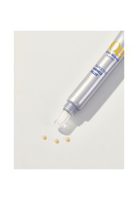 Silberne Tube mit einer klaren Applikatorspitze, beschriftet "Q10 Anti-Aging Experte gezielter Faltenfüller," und drei kleine gelbe Tropfen daneben.
