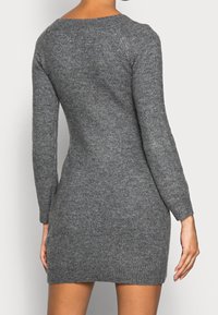 Abito in maglia grigia con maniche lunghe, scollatura rotonda e orlo a costine. Presenta un design aderente e una texture morbida.