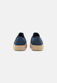 Zapatos de lona azul marino con suelas de yute estilo espadrille, que presentan una puntera redondeada y sin cordones o adornos visibles.