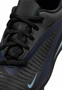 Sort sportsko med en struktureret syntetisk overdel og marineblå detaljer, runde snørebånd og et lysblåt logo på siden.