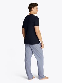 T-shirt a maniche corte blu navale abbinato a pantaloni da pigiama a fantasia blu chiaro. I pantaloni presentano un design a scacchi e una vestibilità rilassata. Senza scarpe.