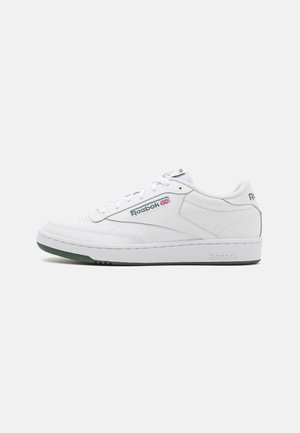 Baskets basses blanches Reebok avec semelle verte, logo Reebok et drapeau Union Jack sur le côté, et fermeture à lacets, vues de côté extérieur.