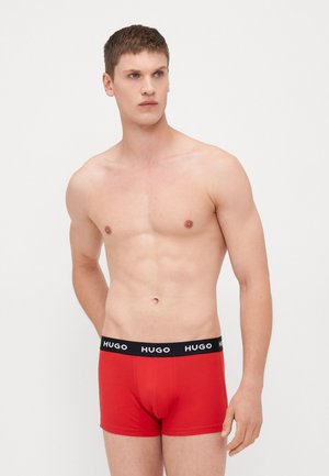 Rote Boxer Shorts aus weichem Stoff mit einem schwarzen elastischen Bund, der das "HUGO"-Logo trägt. Das Design ist körpernah und hat eine mittellange Passform.