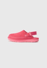 Rosa mocka slip-on skor med bakrem, med en texturerad sula och en slät yta. Varumärket synligt på sidan.