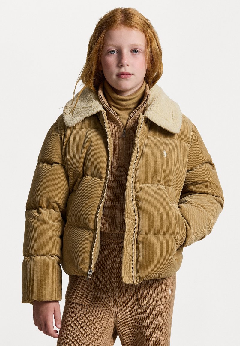 Puhasta jakna iz korduroja v bež barvi, z kremastim sherpa ovratnikom in zadrgo. Teksturirana tkanina z quilted dizajnom.