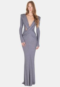 Abito lungo fino al pavimento color argento con glitter, maniche lunghe, scollo a V profondo e design del corsetto intrecciato. Presenta ritagli in vita e ai polsini.