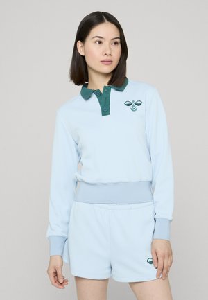 Ensemble sportif bleu clair comprenant un haut à manches longues avec un col vert et un logo, assorti à un short. Texture lisse.