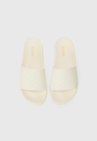 Crème slide sandalen met een gegraveerd patroon, voorzien van een brede voorband en een gevoerde zool. Het "JOOP!" logo is in het goud gedrukt.