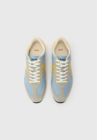 Baskets bleu et grises avec des bandes jaunes, dessus en suédine synthétique et mesh, bout rond, lacets beige, logo de la marque sur la languette, semelle intérieure rembourrée.