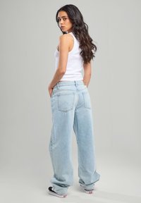 Light blue denim wide-leg jeans with a partially elasticated waistband, back pockets, and a casual fit, paired with a white tank top.