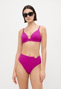 Roza bikini set koji sadrži trokutasti gornji dio s teksturom i zlatnim naglaskom te gaćice visokog struka, oba s podesivim trakama i bočnim detaljima.