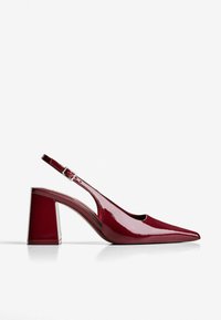 Rote Lackleder-Slingback-Pumps mit spitzer Zehe und Blockabsatz vor weißem Hintergrund.