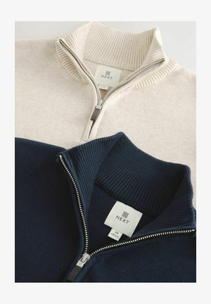 Due maglioni a zip in maglia a coste, uno beige e uno blu navy, ciascuno con un'etichetta del marchio "NEXT" all'interno del colletto.