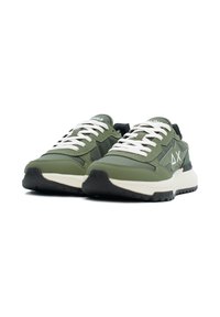 Scarpe da ginnastica verde oliva con lacci bianchi, materiale testurizzato, suola nera spessa e accenti di design geometrico sui lati.