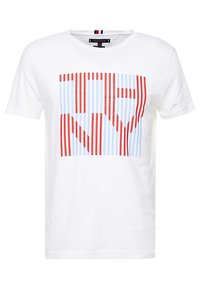 Camiseta blanca de algodón con un diseño gráfico de rayas verticales rojas y azules formando las letras "NY" en el centro.