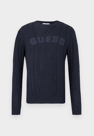 Marineblauwe kabelgebreide trui met geribde manchetten, zoom en "GUESS" tekst geborduurd op de borst.