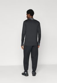 Camisola preta de mangas longas e calças coordenadas feitas de tecido macio. As características incluem um design simples e um ajuste relaxado com punhos elásticos.