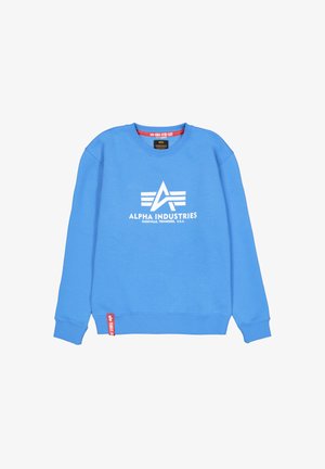 Blå crewneck sweatshirt i bomullsblandning med en vit "Alpha Industries" logo och röd etikett på vänster fåll. Mjuk textur, avslappnad passform.