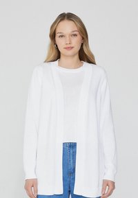 Cardigan blanc avec un design à ouverture frontale, manches longues, poignets et ourlet côtelés, fabriqué en tissu tricot léger. Assorti à un haut blanc.