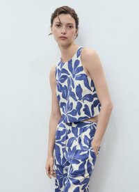 Twee-delige outfit bestaande uit een mouwloze cropped top en hoge taille broek in een crèmekleurige stof versierd met grote blauwe bladerenpatronen.
