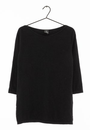 Chemise noire à manches longues avec un col large, fabriquée à partir d'un matériau doux. Présente une étiquette suspendue à l'intérieur du col et un design simple.