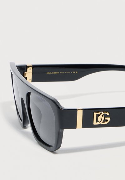 Μαύρα ορθογώνια γυαλιά ηλίου Dolce & Gabbana με σκούρα φακό και χρυσό λογότυπο DG στο πλάι, καθώς και χρυσές λεπτομέρειες κοντά στις μεντεσέδες.