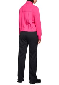 Rosa, kurz geschnittenes Sweatshirt mit hohem Kragen, elastischem Bund und langen Ärmeln, kombiniert mit lockeren schwarzen Hosen mit strukturierter Oberfläche.