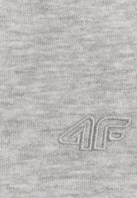 Tissu tricoté gris avec un logo brodé en relief montrant les lettres "4F" en fil gris assorti.