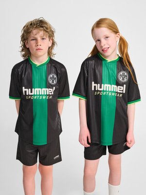 To børn står side om side iført sorte og grønne Hummel sportstøj fodbolduniformer mod en ensfarvet baggrund.
