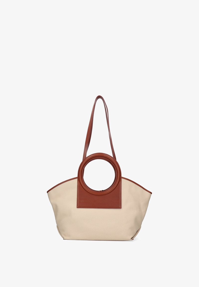 Beige lærredshåndtaske med brune lædercirkulære håndtag og lang skulderrem, struktureret trapezform.