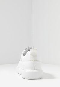 Sneaker bianco in pelle liscia, con punta rotonda, colletto imbottito e linguetta di tacco in tessuto. Design minimalista con suola strutturata.