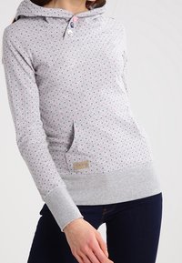 Ljusgrå hoodie med ett prickigt mönster i rosa och blått. Har en frontficka, elastiska mudd och en tvåknapps halsöppning.