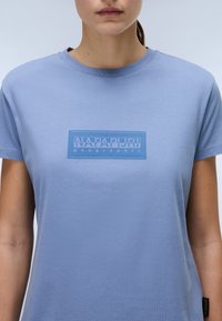 Lyseblå kortærmet t-shirt lavet af blødt bomuld. Har et rektangulært logo i en mørkere blå. Klassisk rund hals og standard pasform.