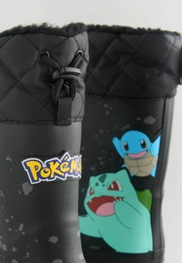 Zwarte rubberen regenlaarzen hebben een gequiltte textuur aan de bovenkant, versierd met Pokémon-graphics, waaronder Squirtle en Bulbasaur, en een logo.