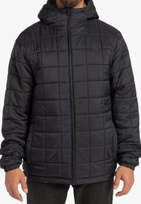 Giacca imbottita nera con cappuccio, caratterizzata da un design trapuntato, chiusura frontale con zip, polsini elasticizzati e tasche laterali. Materiale morbido e leggero.