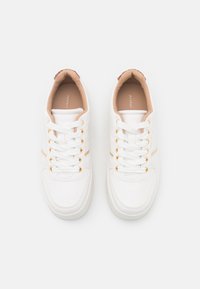 Weiße Sneakers mit einer glatten Lederoberfläche, goldenen Ösen und hellbeigen Akzenten im Krageninneren. Klassisches Schnürdesign.