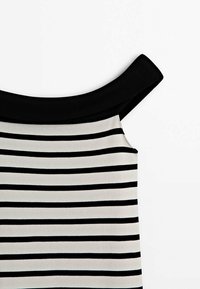 Haut sans manches à rayures horizontales noires et blanches avec un large col noir et des bretelles noires sur fond blanc.