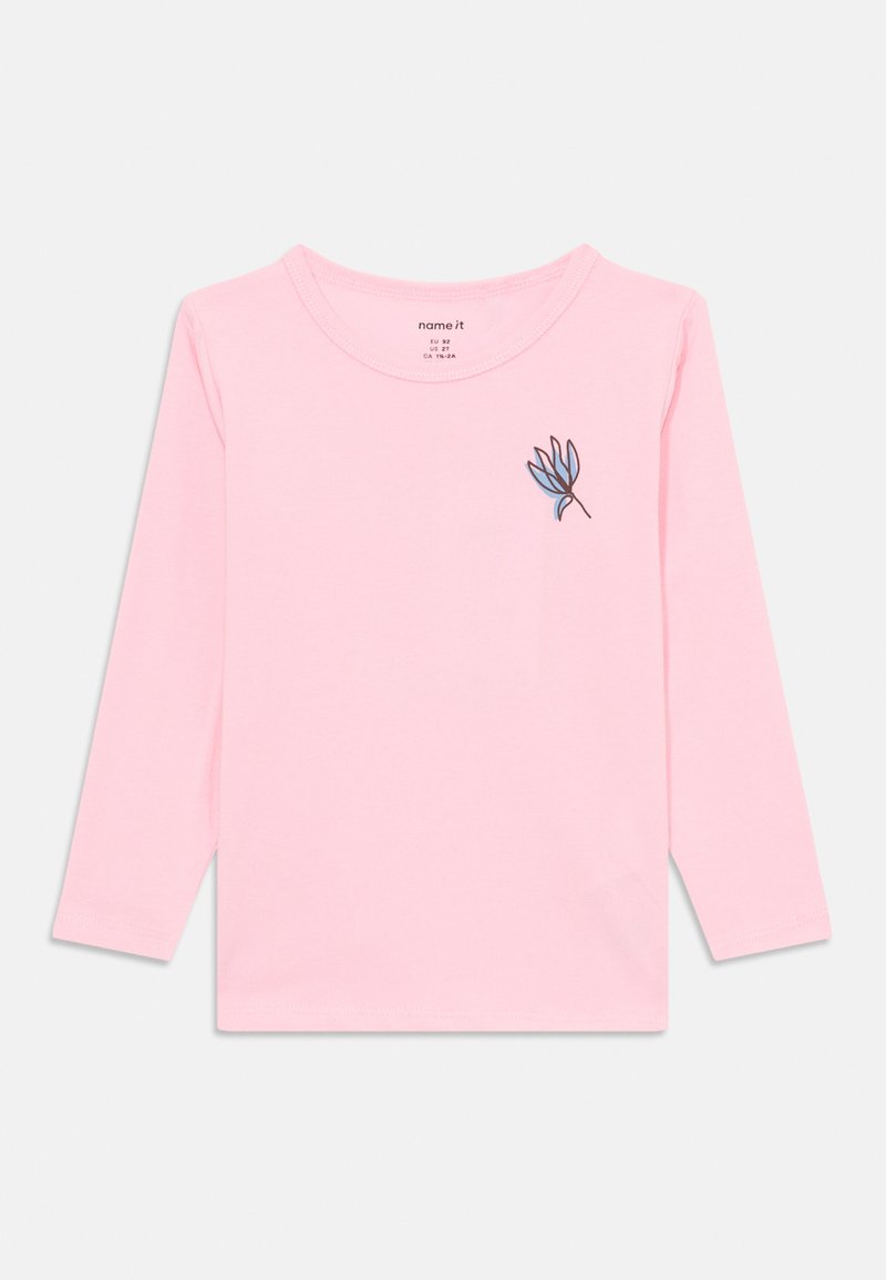 T-shirt à manches longues rose pâle en coton, avec une petite broderie florale bleue et marron près de la poitrine. Encolure ronde, texture douce.