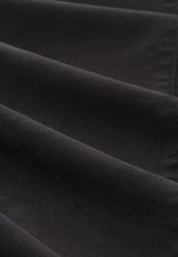 Juodas audinys su lygiu tekstūru ir įstrižainės audimu. Medžiaga atrodo patvari ir natūralioje šviesoje turi subtilų blizgesį.