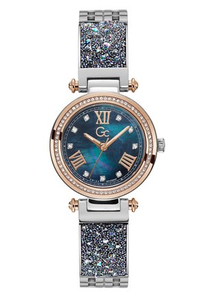 Round watch with a dark blue face, rose gold accents, Roman numerals, and a silver-tone band featuring textured, sparkly details.
