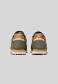 Sneaker in suede verde con un accento in pelle beige e una suola intermedia in gomma bianca. Presenta un tallone testurizzato e una suola in gomma nera per una migliore aderenza.