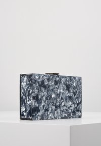 Clutch a busta in un materiale blu scuro testurizzato, con una superficie frammentata lucida, forma rettangolare e chiusura a scatto metallica sulla parte superiore.