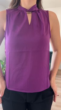 Violet bežė rankovių palaidinė su raktu formos iškirpte ir susiraukšlėtu apykaklės detalėmis. Pagaminta iš lygaus audinio, dėvima su juodomis kelnėmis.