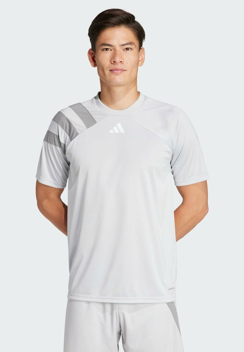 Lichtgrijs sportshirt met korte mouwen, voorzien van een ronde halslijn en diagonale grijze patronen op de schouders. Adidas-logo aan de voorkant.