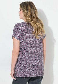Top de manga corta en una tela ligera, con un estampado de leopardo en rosa y negro sobre un fondo claro, y un corte relajado.