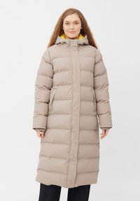 Lang, beige pufferjakke med vertikal quiltet design, hætte og dybe sidelommer. Indersiden har en kontrastfuld gul foring.