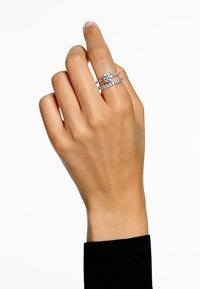Inel de logodnă cu diamant, montat în argint, av�ând o piatră centrală rotundă, accentuată cu pietre mai mici pe două benzi delicate.